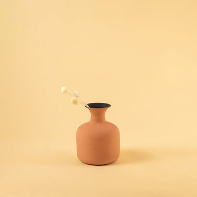 Terracotta matte finish vase styled with dried botanical stems adding a warm natural touch to a calm beige interior setting with soft light enhancing the decor.