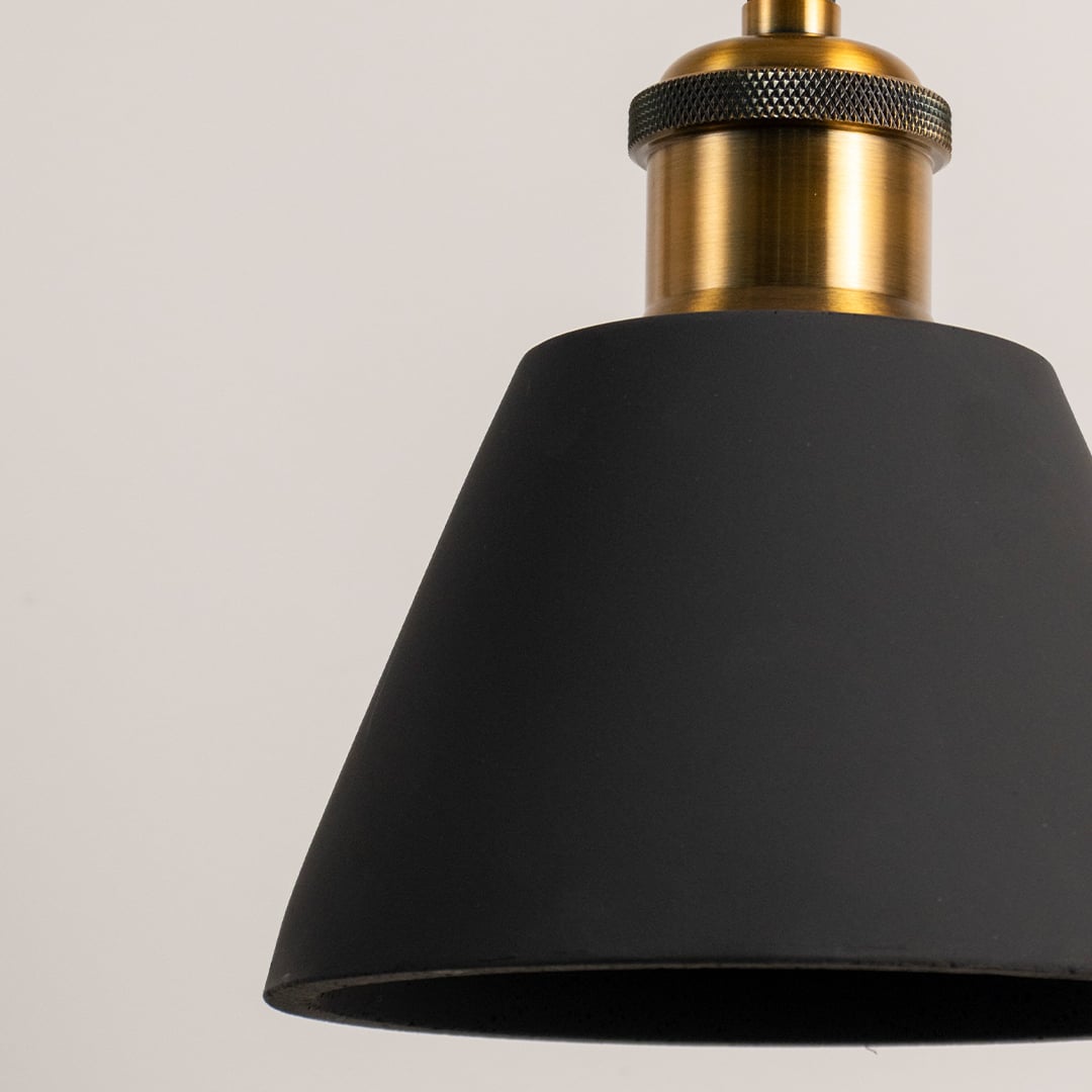 Closeup of black cone pendant lamp turned off with golden brass detail and matte black finish.
