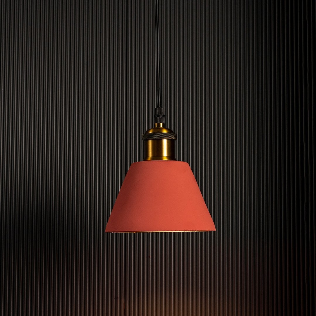 Terracotta cone pendant light glowing brightly against a dark background emphasizing its stylish silhouette.