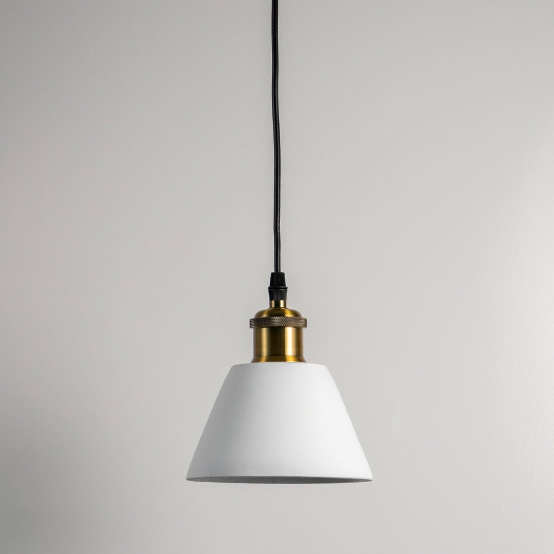 White cone pendant light turned off against white wall showcasing clean lines and brass top in minimal modern style.