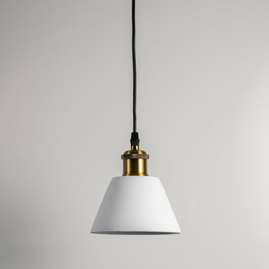 White cone pendant light turned off against white wall showcasing clean lines and brass top in minimal modern style.