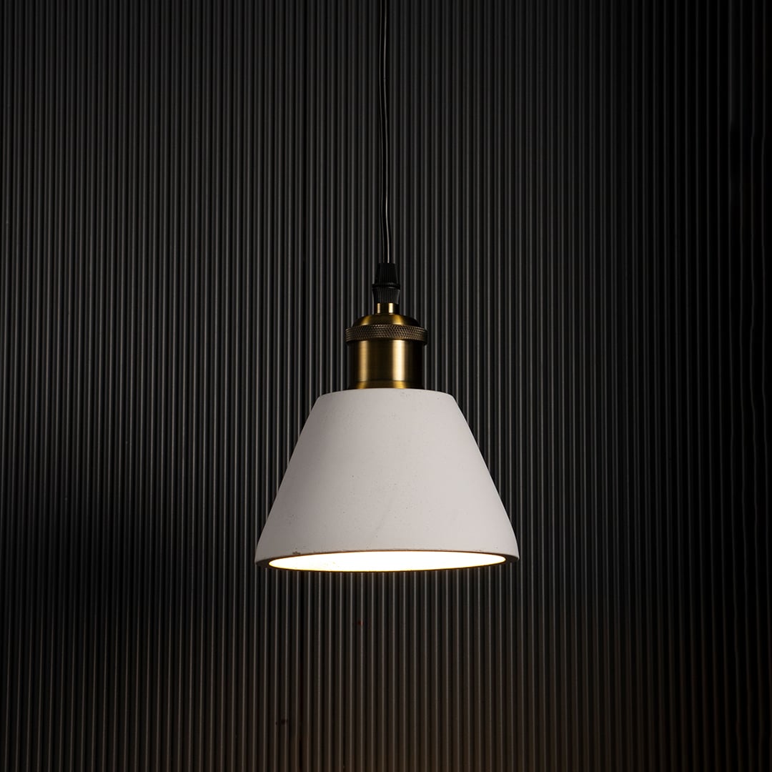 Black cone pendant light turned on glowing warmly against dark background highlighting brass detailing and elegant finish.