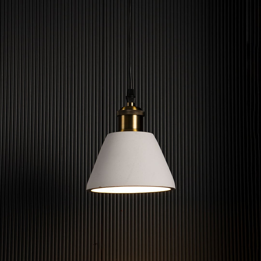 Black cone pendant light turned on glowing warmly against dark background highlighting brass detailing and elegant finish.