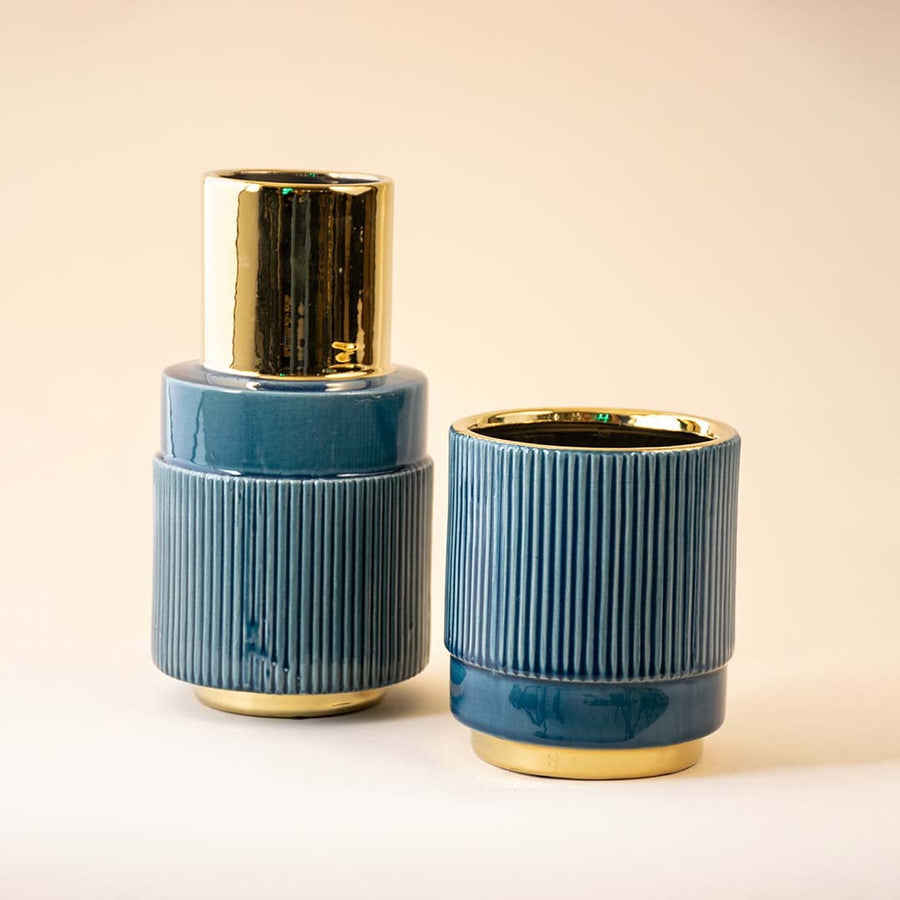 Grouped blue and gold ceramic vases with light on highlighting their ribbed textures glossy finishes and contemporary shapes for coordinated decor styling.