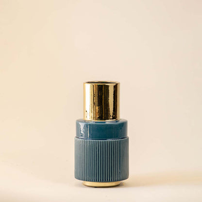 Blue ceramic decorative vase with ribbed texture and gold neck detail for elegant contemporary home decor styling.