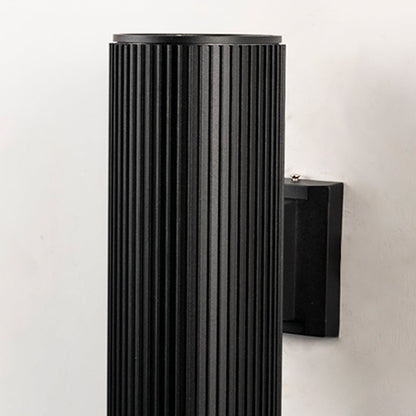 Closeup of black ribbed cylindrical wall light showing detailed metal texture and refined craftsmanship.
