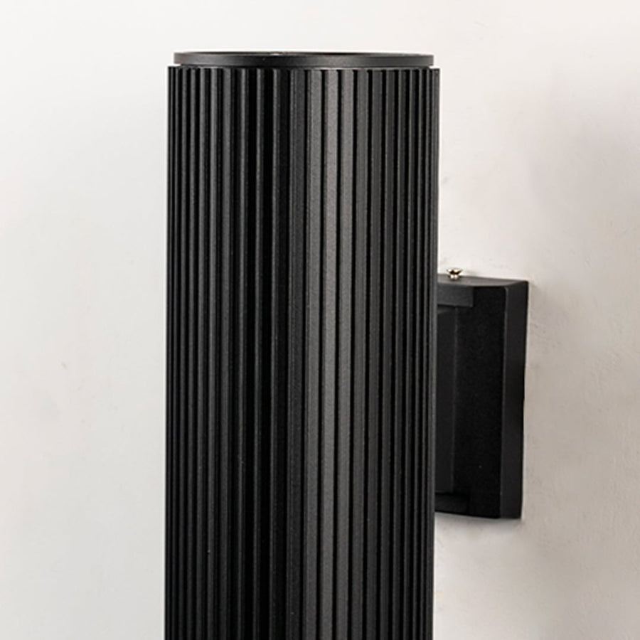 Closeup of black ribbed cylindrical wall light showing detailed metal texture and refined craftsmanship.
