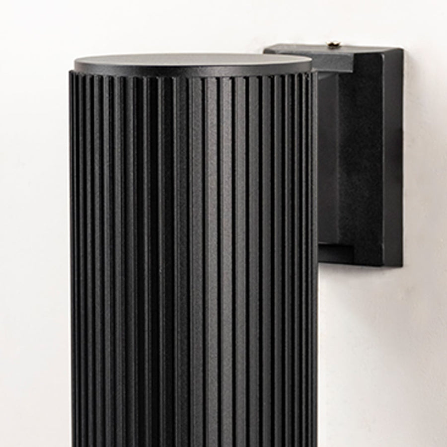 Closeup of black cylindrical wall light highlighting grooved texture and matte metal surface with clean edges.