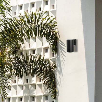 Sleek black cylindrical wall light illuminating a modern living space with soft ambient glow and minimalist architectural charm.