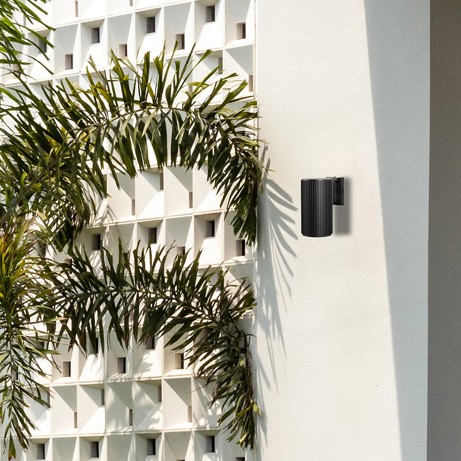 Sleek black cylindrical wall light illuminating a modern living space with soft ambient glow and minimalist architectural charm.