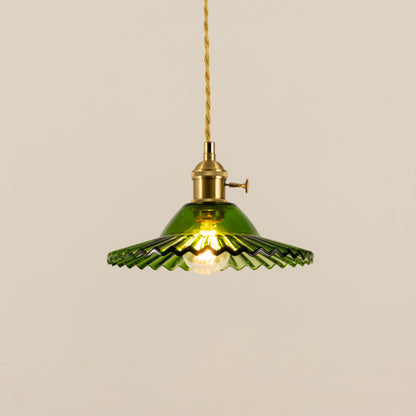 Illuminated green fluted metal pendant light with brass accents creating warm ambient lighting indoors.