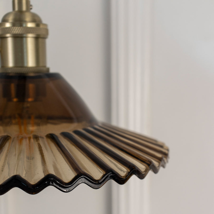 Closeup of bronze metal pendant light with fluted shade showcasing intricate details and craftsmanship.