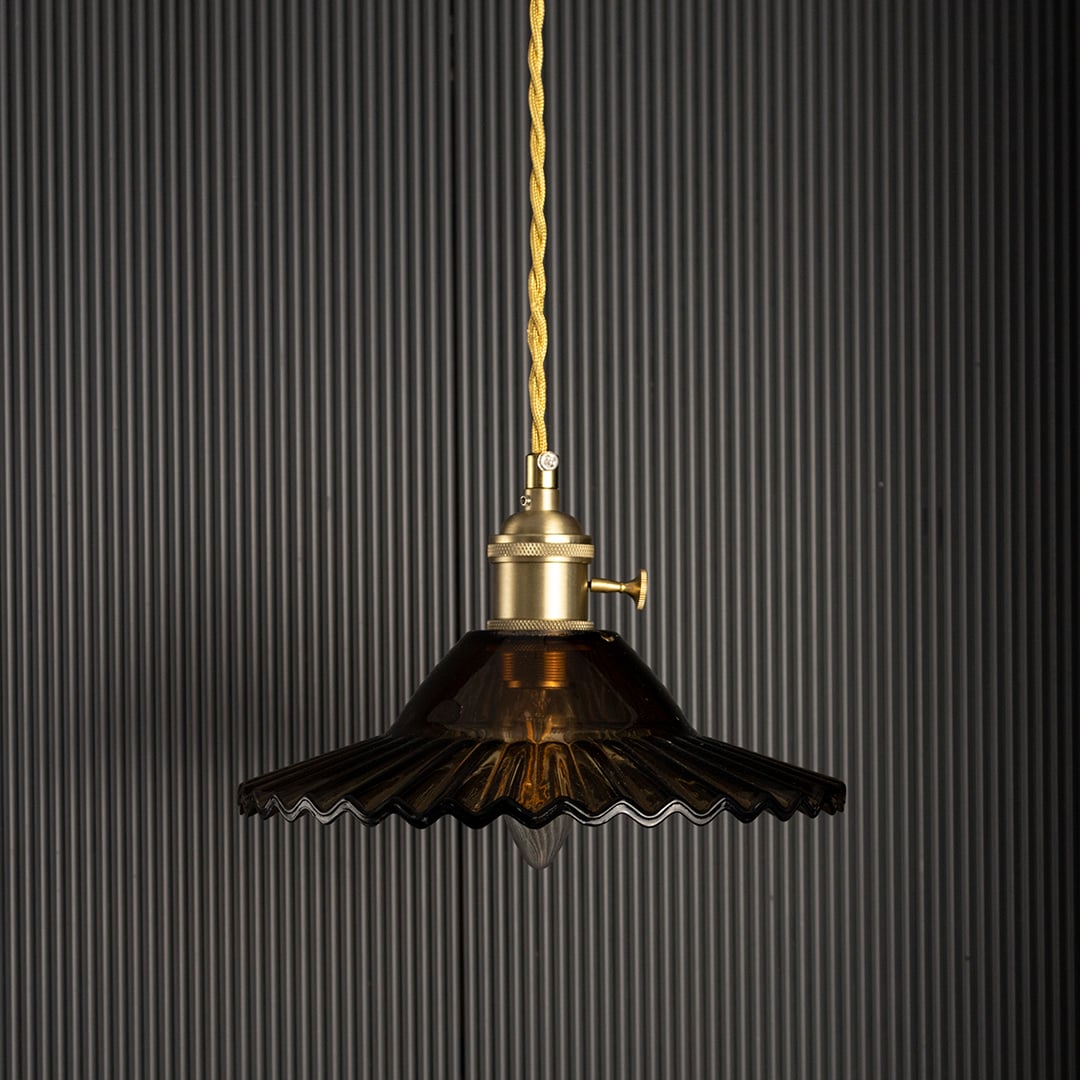 Luxury pendant light with gold metal shade glowing on black background creating dramatic ambience for modern home interiors.