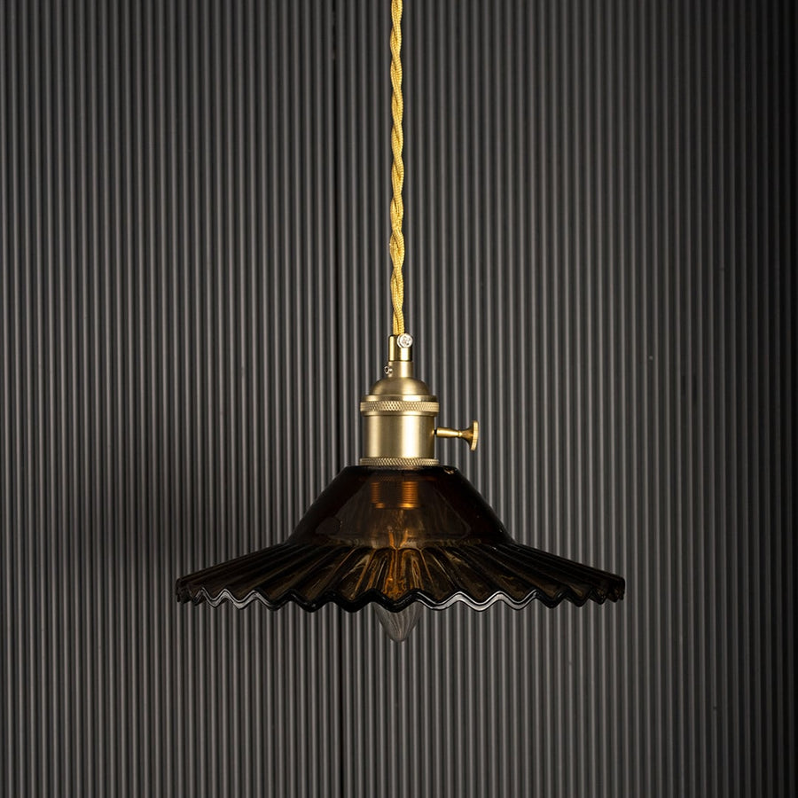 Luxury pendant light with gold metal shade glowing on black background creating dramatic ambience for modern home interiors.