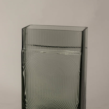 Closeup of textured smoky gray glass vase showcasing fine ribbed surface and geometric circular detailing.