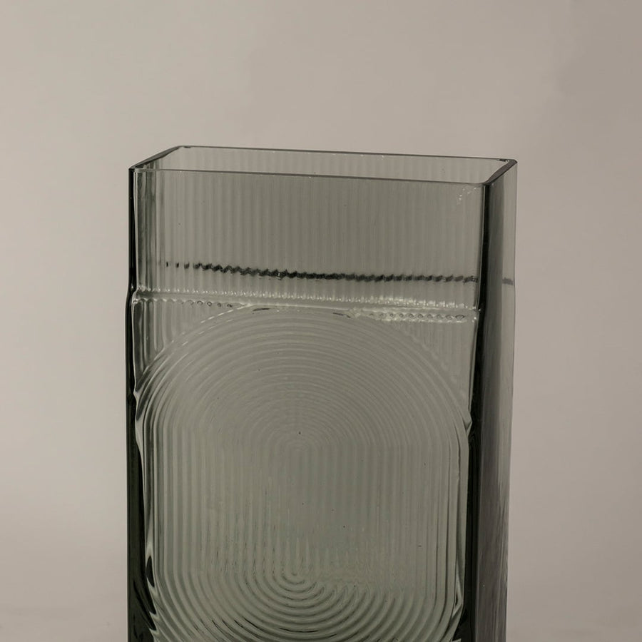 Closeup of textured smoky gray glass vase showcasing fine ribbed surface and geometric circular detailing.