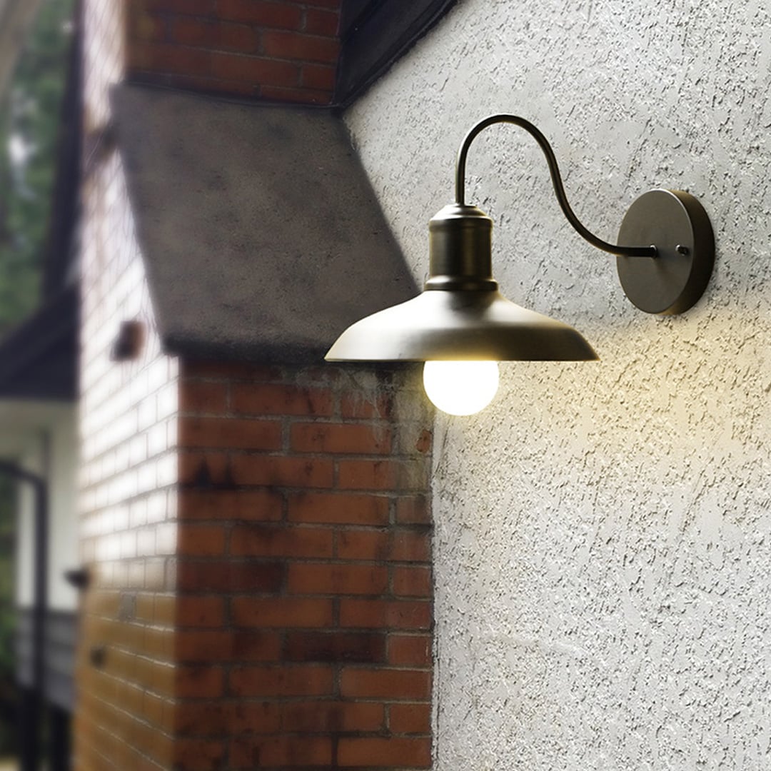 Matte black metal outdoor wall light glowing warmly on a textured exterior wall creating cozy ambient lighting for modern outdoor spaces.