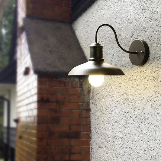 Matte black metal outdoor wall light glowing warmly on a textured exterior wall creating cozy ambient lighting for modern outdoor spaces.