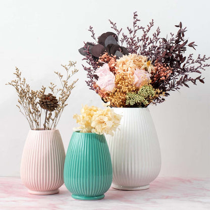 Set of three ribbed ceramic vases in white teal and pink shades each with unique floral arrangements for elegant tabletop styling.