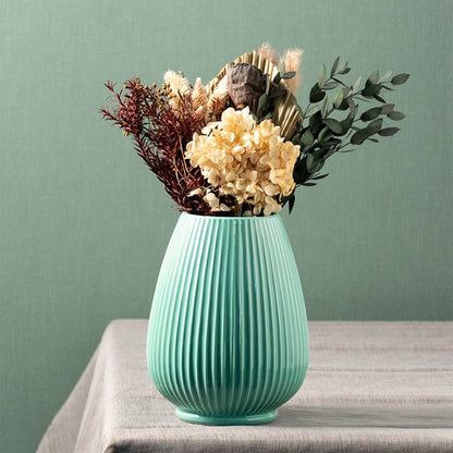 Stylish green ceramic vase with dried flowers placed on table for modern living room and dining decor.
