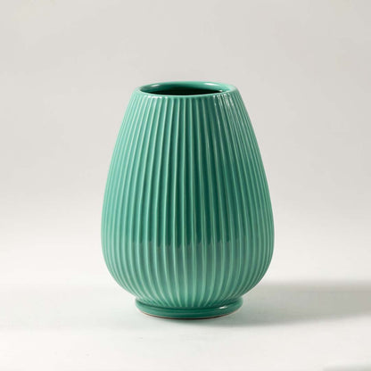 Green ceramic decorative vase with ribbed texture and rounded form for elegant tabletop styling and home decor.