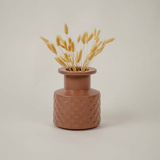 Brown ceramic vase with geometric texture styled beside dried flowers brings organic charm to living room decor.