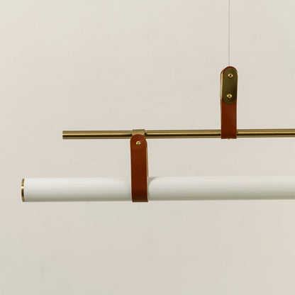 Closeup of gold linear pendant light showing white tubular diffuser leather strap accents and refined craftsmanship.