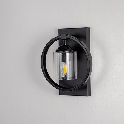 Black circular frame wall light with clear glass shade and exposed bulb shown off on white background for modern interiors.