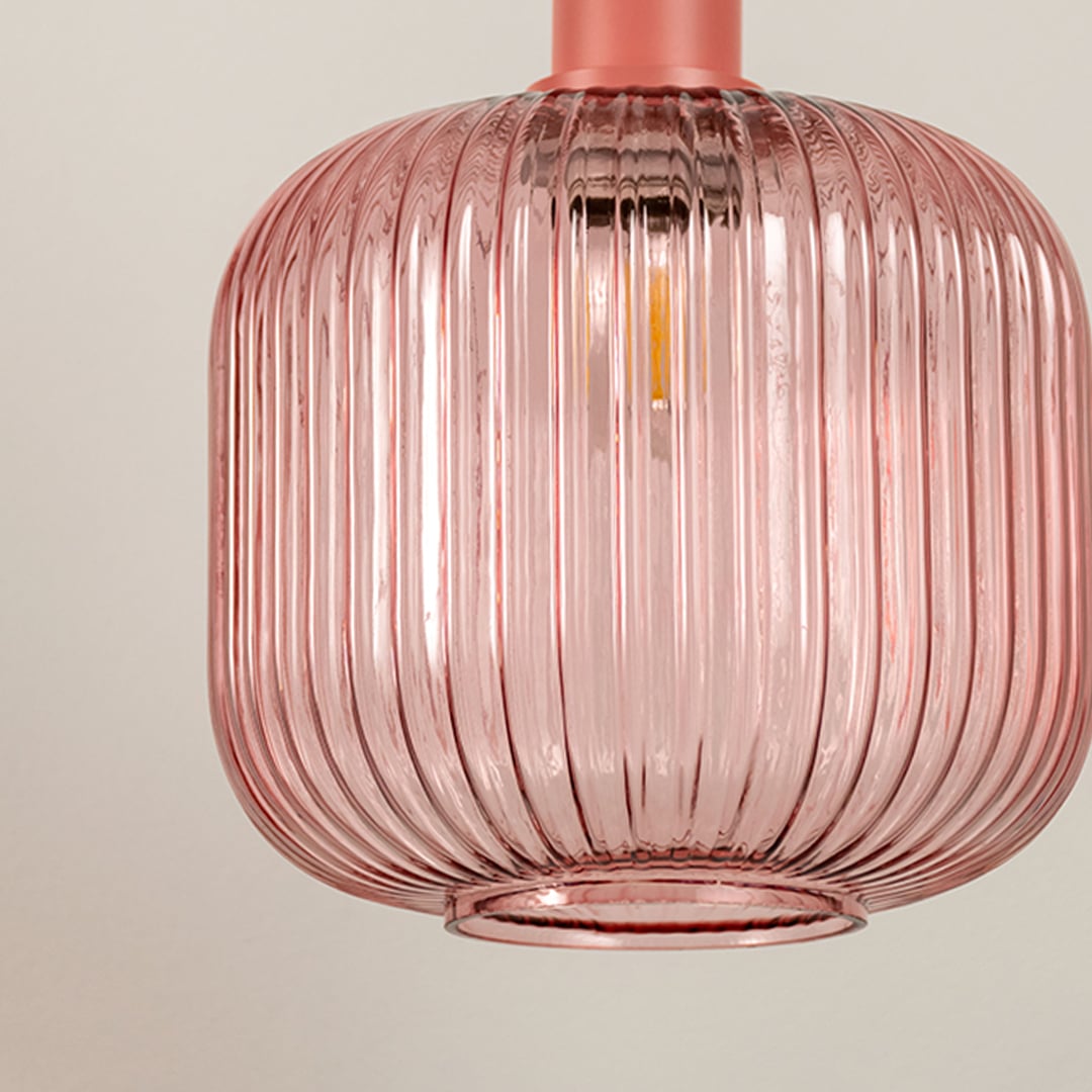 Closeup of pink ribbed glass pendant light highlighting rounded shape translucent texture and elegant modern lighting craftsmanship.