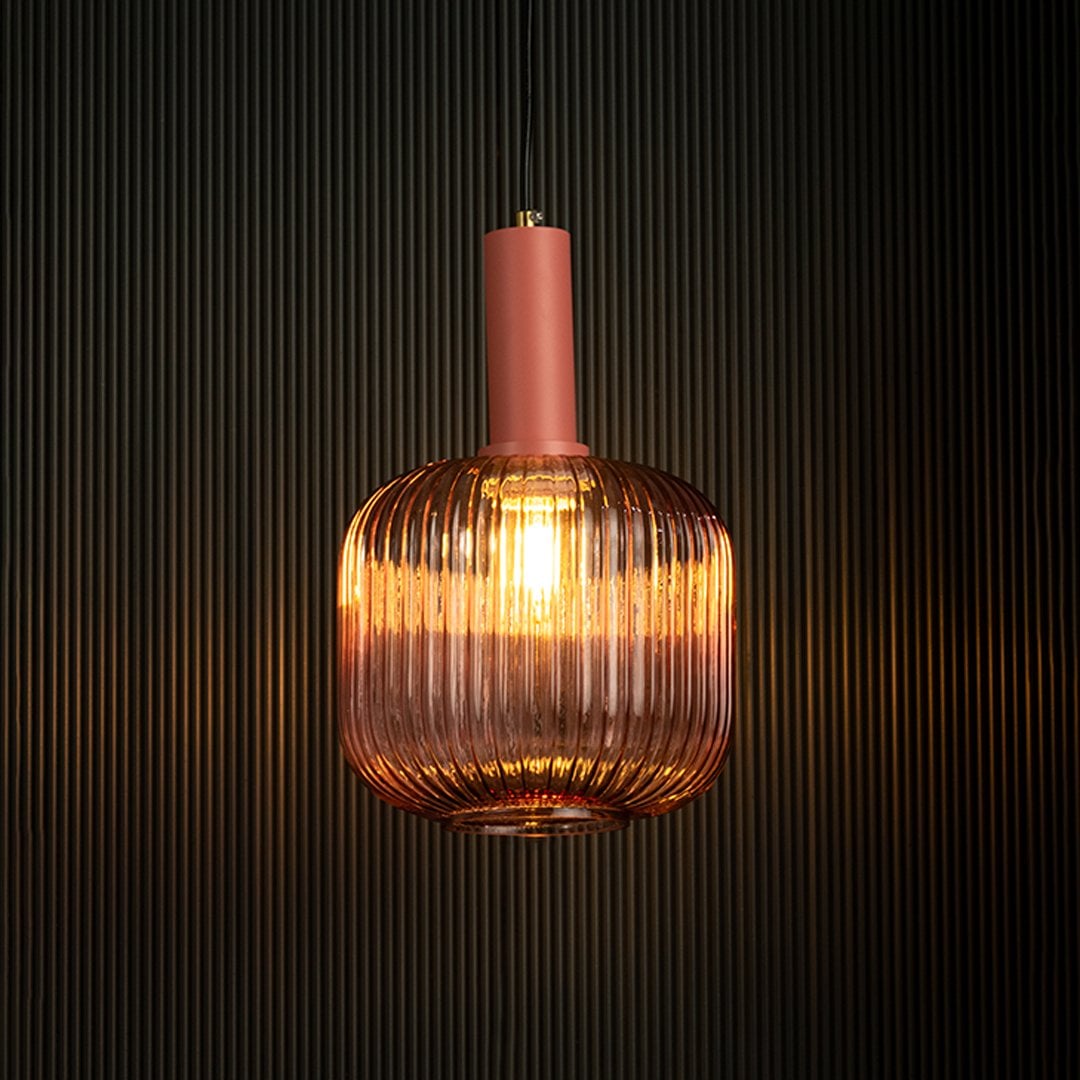 Modern pink glass pendant light glowing vividly on dark background.