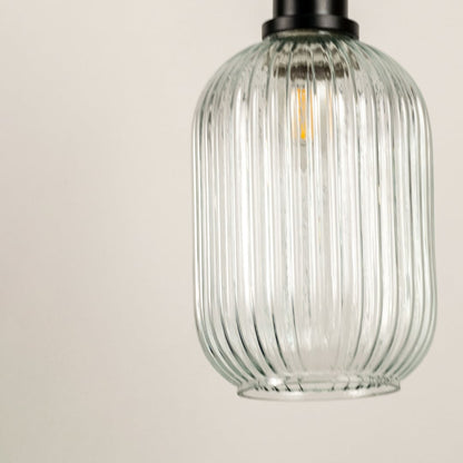 Detailed closeup of ribbed glass pendant lamp with black holder showcasing modern lighting texture and craftsmanship.