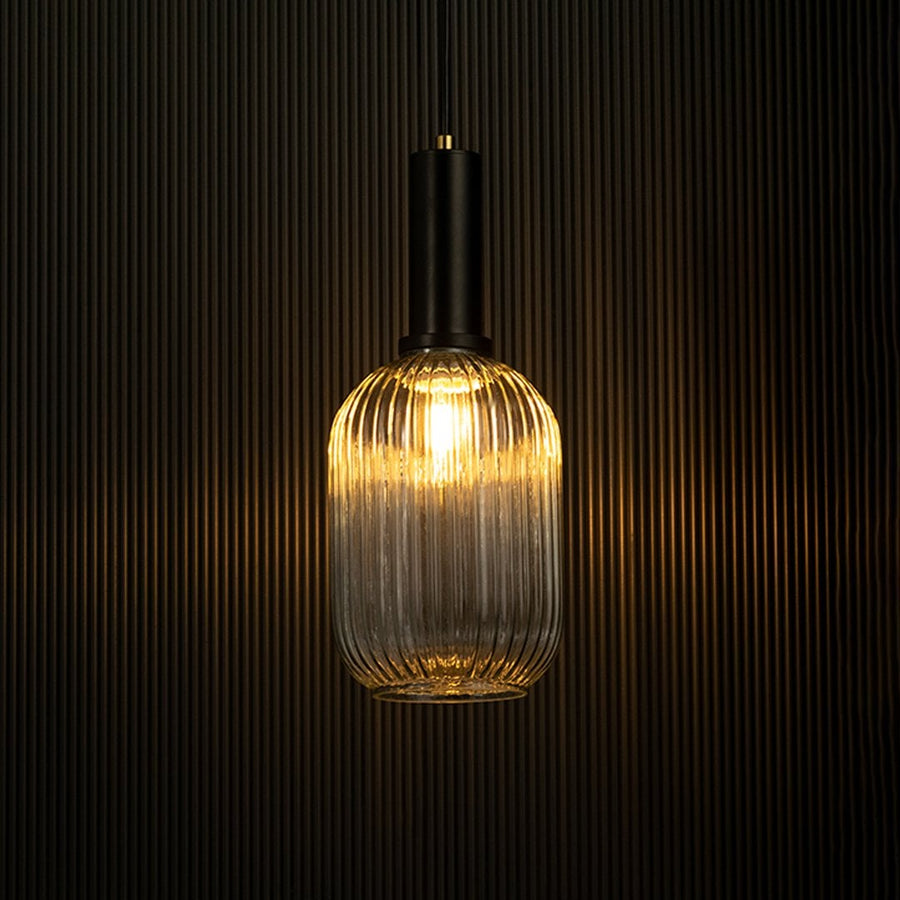 Stylish ribbed glass pendant light with black holder glowing against dark background for dramatic effect.