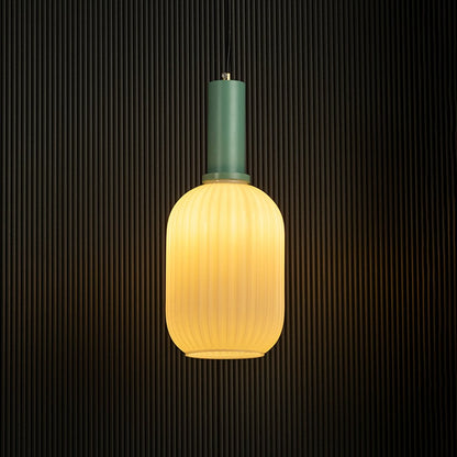 Contemporary ribbed glass pendant light with green finish glowing against a dark background.