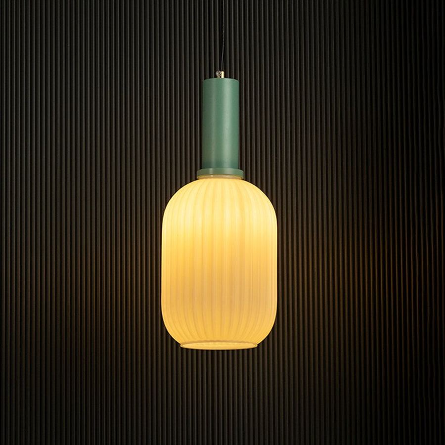 Contemporary ribbed glass pendant light with green finish glowing against a dark background.