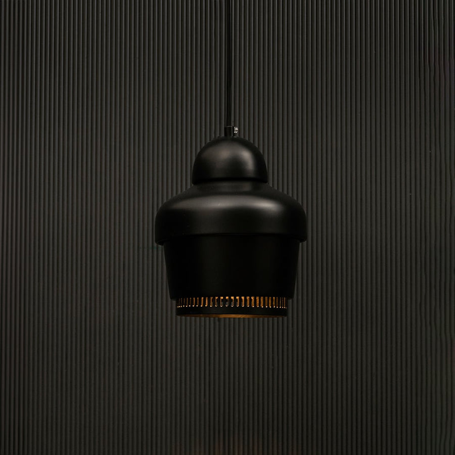 Black industrial pendant light with ribbed detailing against dark panel wall with light on for contemporary décor.