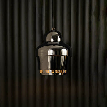 Chrome industrial pendant light with ribbed detailing against dark panel wall with light on for sleek modern décor.