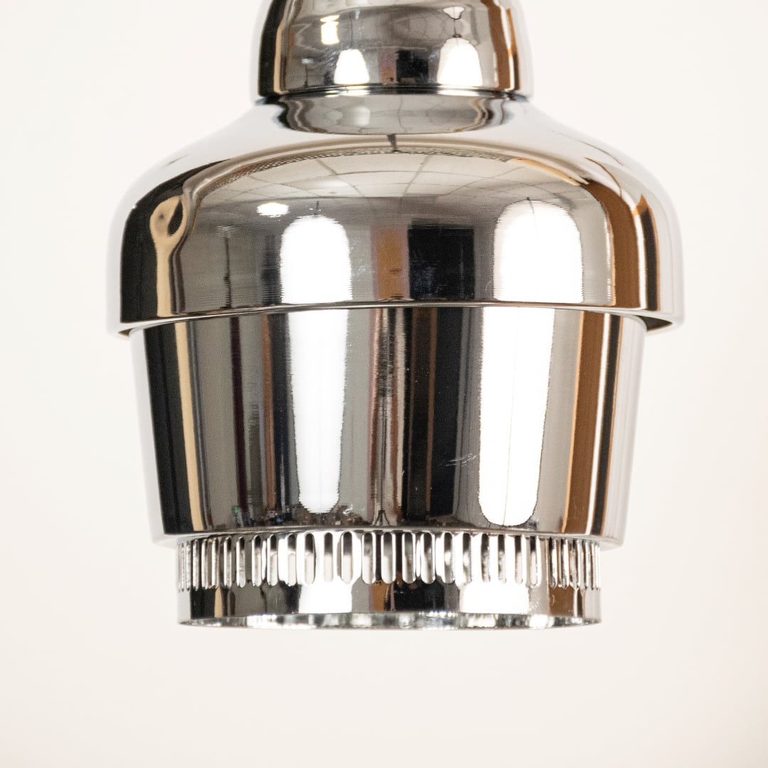 Chrome industrial pendant light shown in close up view with ribbed detailing against plain background for sleek modern décor.