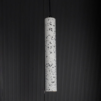 Terrazzo pendant light turned on against dark backdrop highlighting its speckled finish and refined minimalist design.