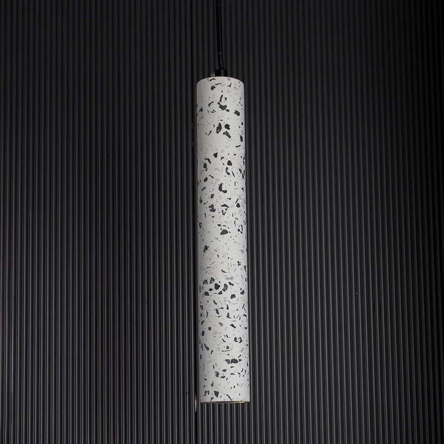 Terrazzo pendant light turned on against dark backdrop highlighting its speckled finish and refined minimalist design.