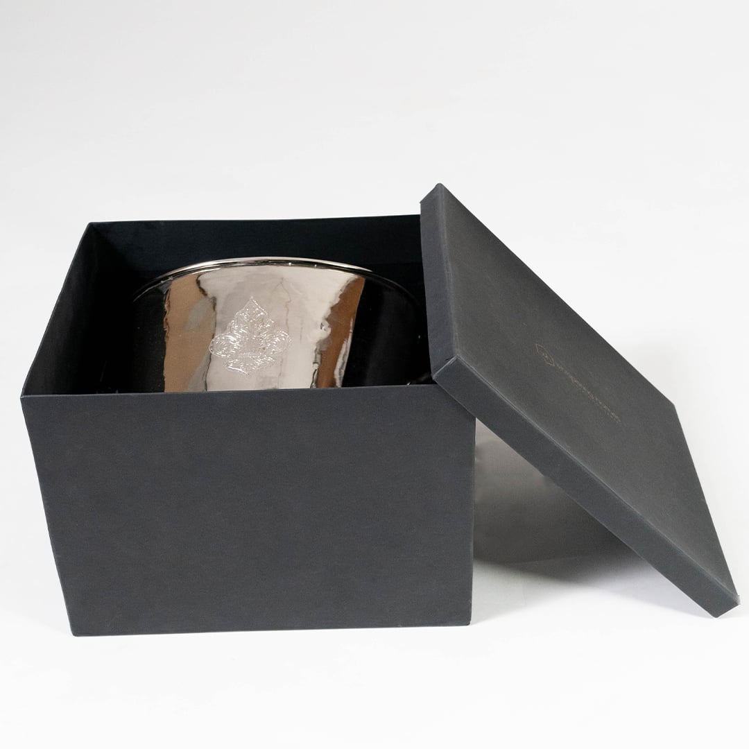 Silver champagne bucket partially placed inside a black gift box on a clean white background showing its engraved detailing and elegant reflective finish.