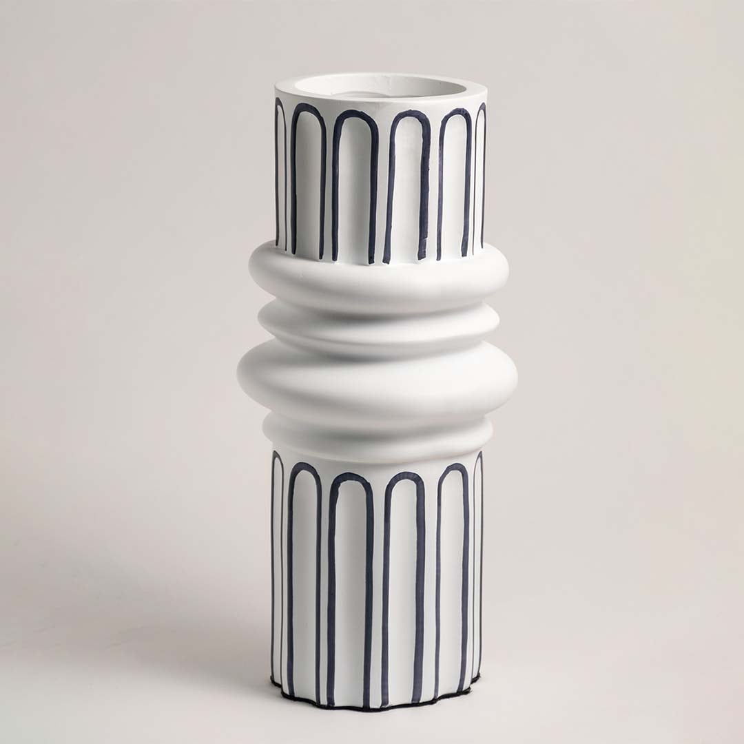 White ceramic vase with artistic blue line detailing showcased on a white background under soft lighting.