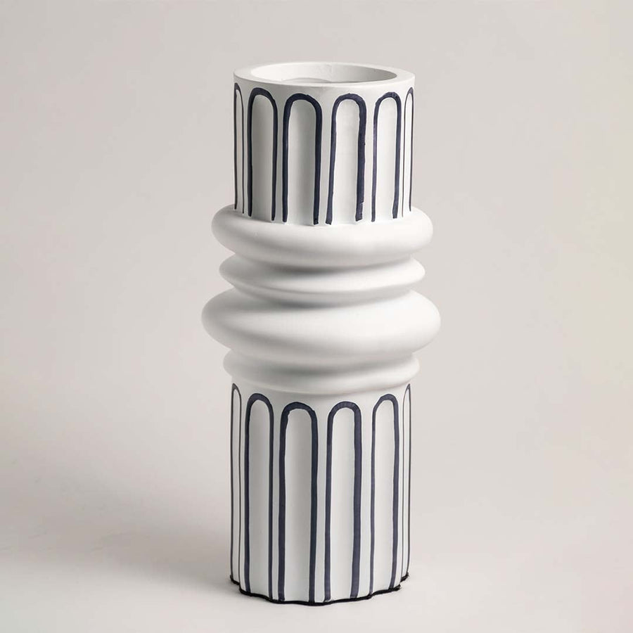 White ceramic vase with artistic blue line detailing showcased on a white background under soft lighting.