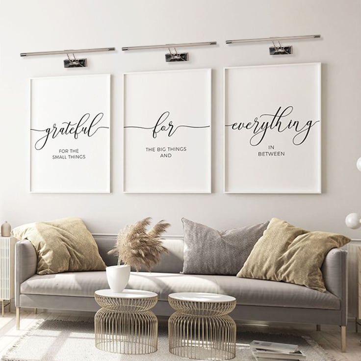 Elegant chrome picture light glowing softly on a neutral wall perfect for modern living room and gallery style home lighting.