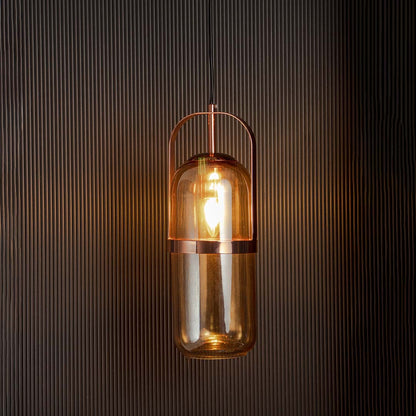 Amber glass pendant light glowing warmly with golden frame against black background creates cozy ambient decor.