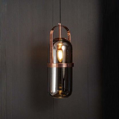 Modern smoked glass pendant light with copper accents glowing warmly against black background.
