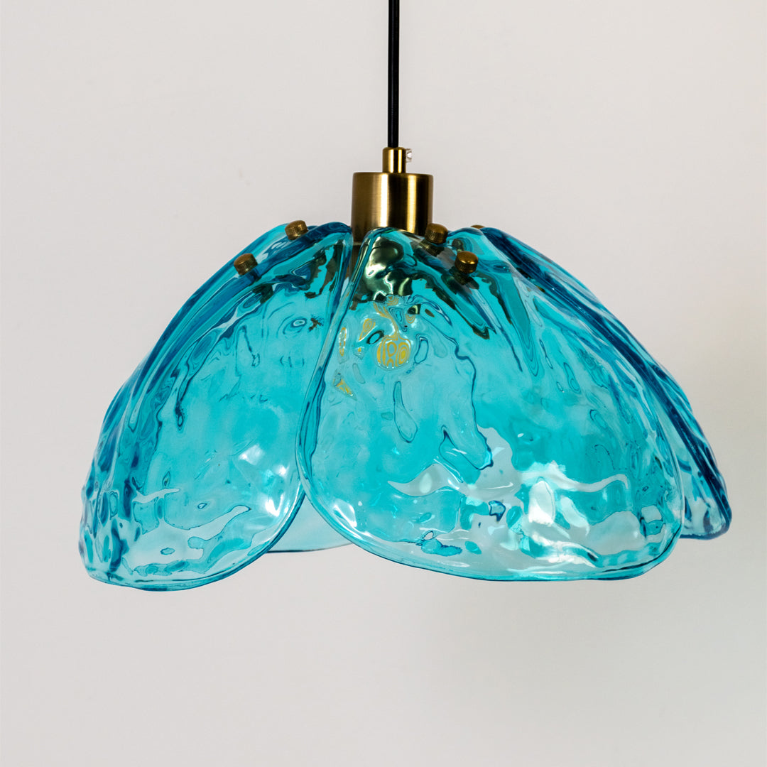 Closeup pendant light in gold metal finish with blue textured glass shade for dining room or kitchen decor lighting white background.