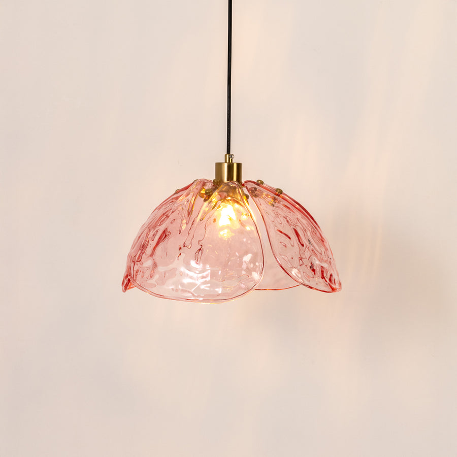 Decorative pendant light in gold metal finish with pink glass shade for dining room or kitchen decor lighting white background.