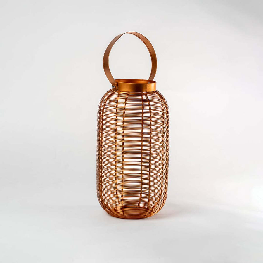 Copper metal mesh cylindrical lantern with circular carrying handle and ribbed texture design on isolated white background.