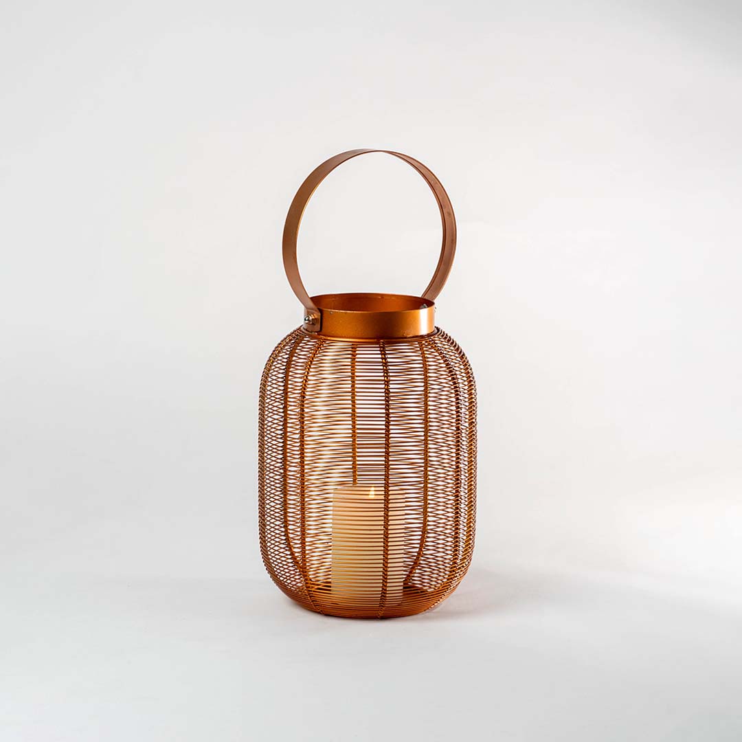 Copper metal mesh lantern with round handle and candle holder for elegant tabletop decor styling.