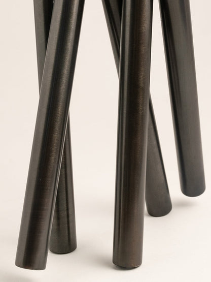 Detailed view of tubular black metal vase design with polished finish and clean lines.